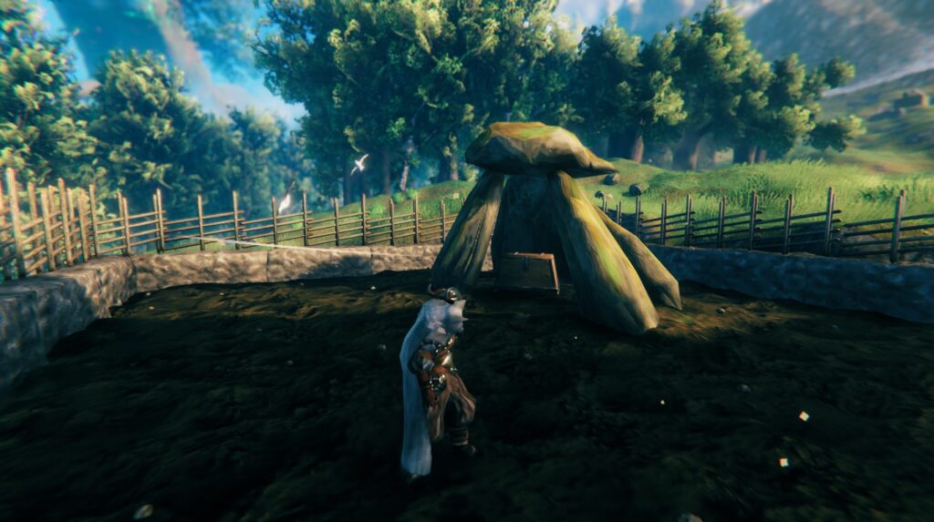 Screenshot from the game Valheim. It shows my character standing in front of a dolmen with a few rather tilted standing stones and one top stone balanced precariously on top.

In the hollow underneath the top stone sits a large chest. A walled garden surrounds the dolmen, with the dirt looking dark and fertile.